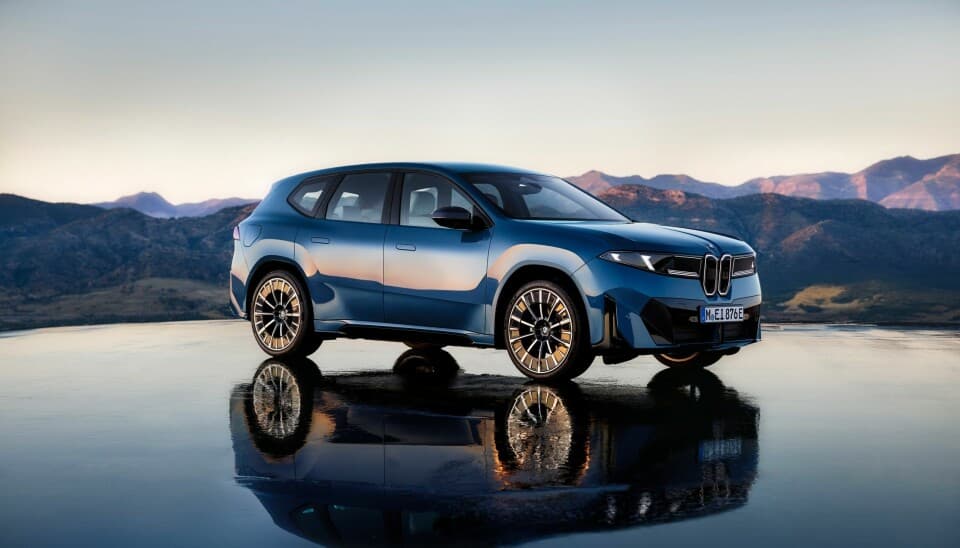 Der BMW iX3 in Dreiviertelansicht vor modernem Gebäude