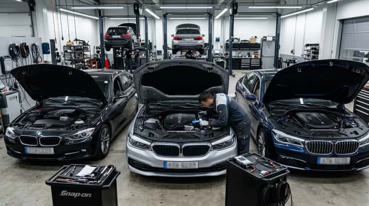 Werkstattszene mit geöffneter Motorhaube eines BMW, Techniker inspiziert Motorstarter
