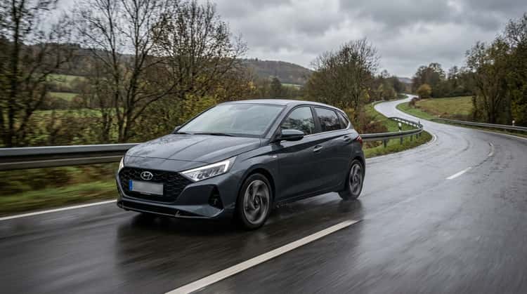 Ein Hyundai i20 Kleinwagen fährt auf einer feuchten Landstraße, Testfahrzeug für Ganzjahresreifentest