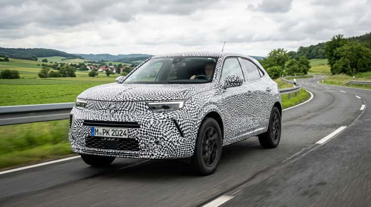 Erlkönig eines kommenden elektrischen Opel SUV mit Allradantrieb in Tarnfolien auf einer Landstraße, Nachfolger des Mokka