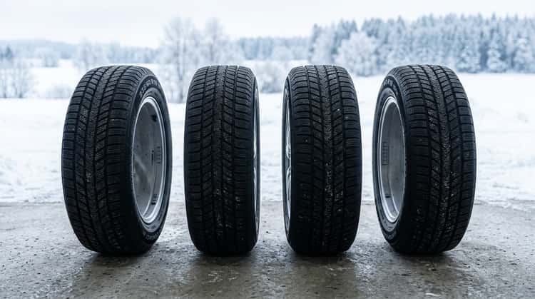 Vier Winterreifen der Größe 235/60 R18 mit Alpine-Symbol nebeneinander auf grauem Untergrund